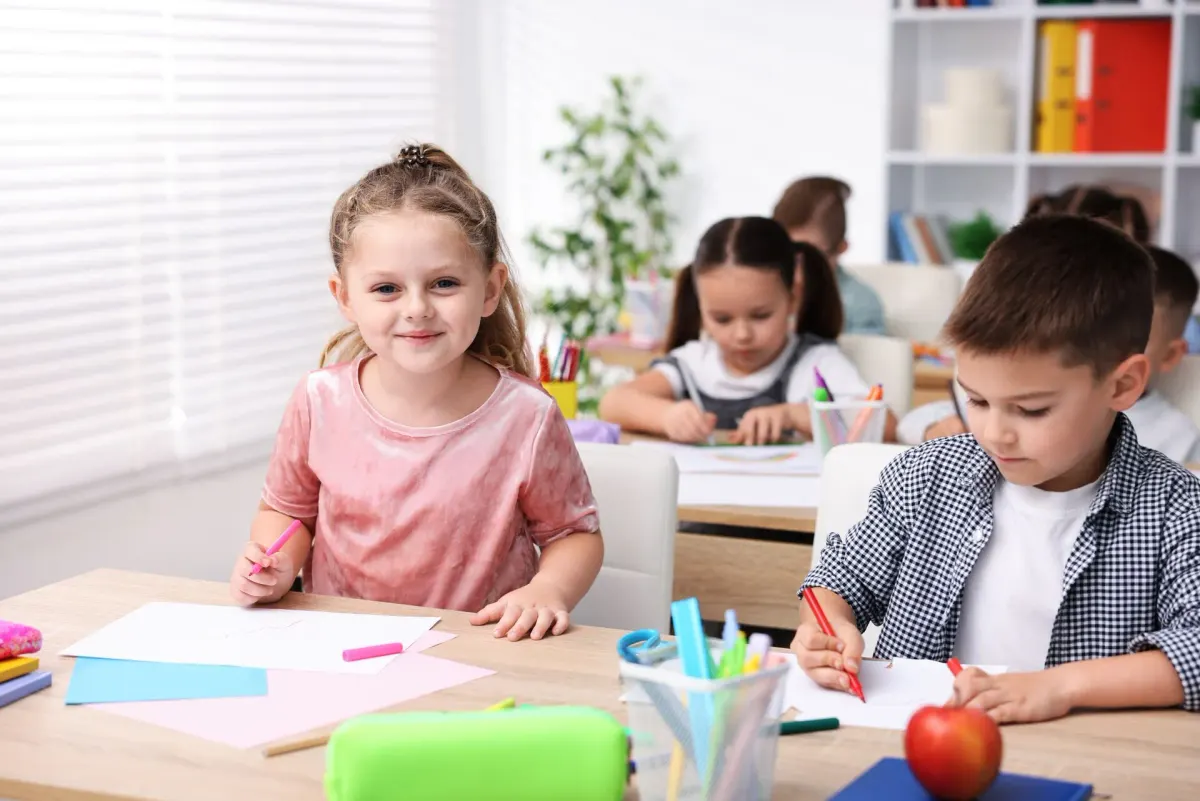 Grundschulkinder malen und schreiben an ihren Tischen im Klassenzimmer