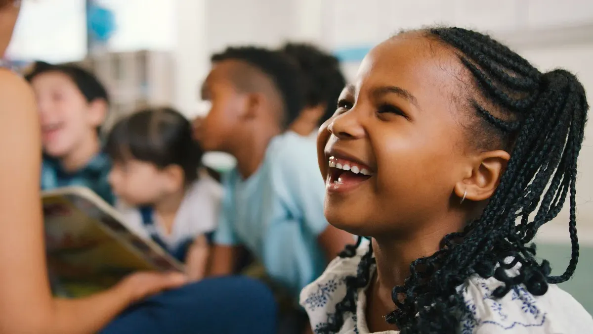 Lachende Schülerin in einer Klasse, weitere Kinder im Hintergrund